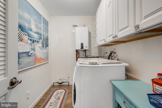 clothes washing area featuring water heater, washing machine and clothes dryer, hardwood / wood-style flooring, and cabinets