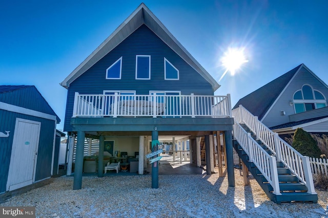 rear view of property featuring a storage unit, a wooden deck, and a patio