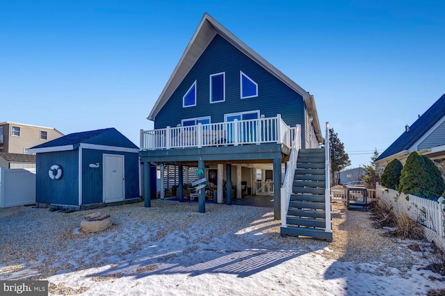 snow covered property featuring a wooden deck and a shed