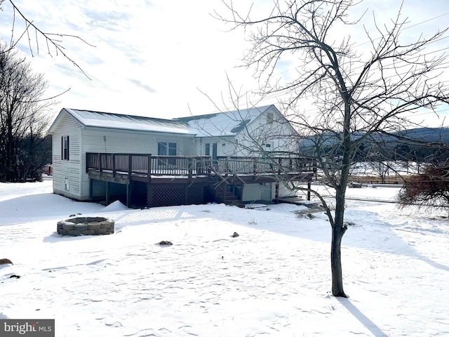 snow covered back of property featuring a fire pit and a wooden deck