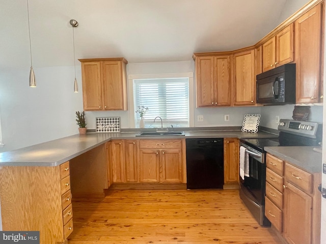 kitchen with black appliances, sink, decorative light fixtures, light hardwood / wood-style floors, and kitchen peninsula