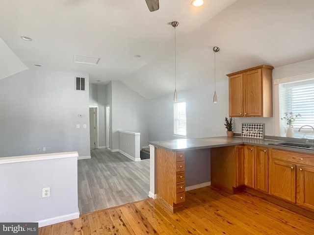 kitchen featuring kitchen peninsula, sink, pendant lighting, and light hardwood / wood-style floors