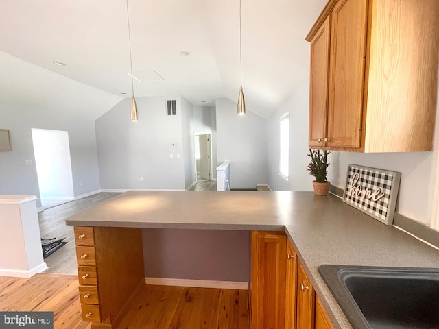 kitchen featuring kitchen peninsula, pendant lighting, light wood-type flooring, and lofted ceiling