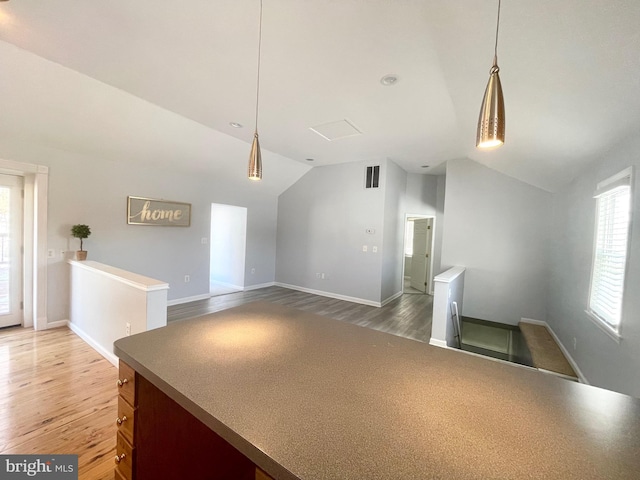 kitchen featuring hardwood / wood-style flooring, lofted ceiling, and hanging light fixtures