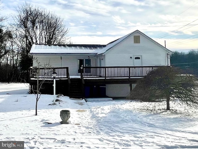 snow covered rear of property with a deck