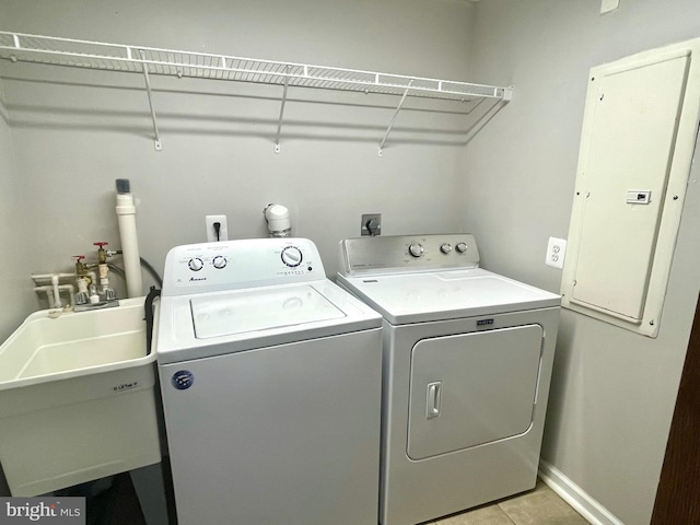 laundry room with light tile patterned floors, electric panel, separate washer and dryer, and sink