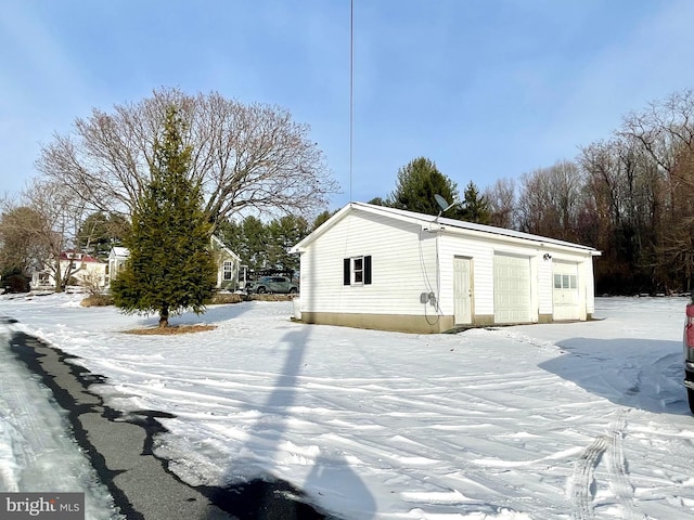 snow covered structure featuring a garage