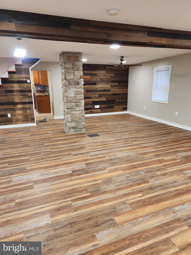 basement with light hardwood / wood-style flooring and wooden walls