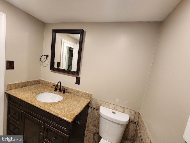 bathroom featuring vanity, tile walls, and toilet