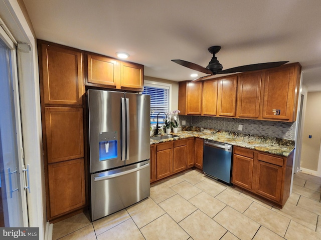 kitchen with backsplash, sink, ceiling fan, light stone counters, and stainless steel appliances