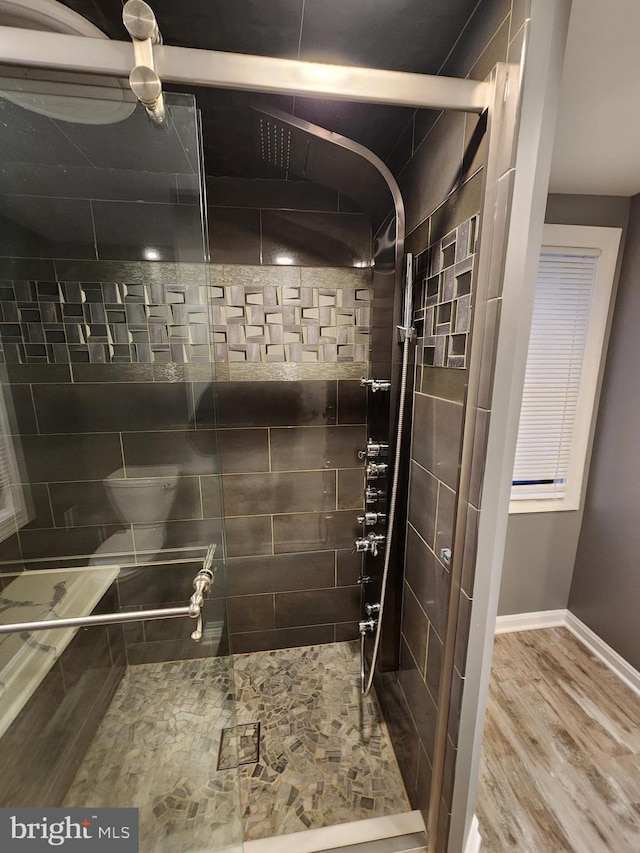 bathroom featuring hardwood / wood-style flooring and tiled shower