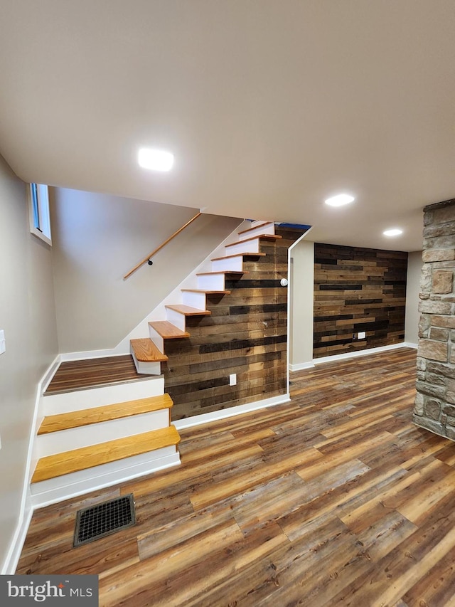 stairs featuring wood-type flooring and wood walls