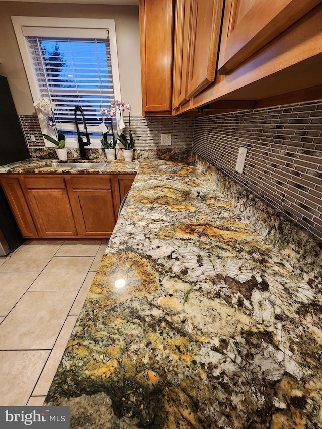 kitchen with sink, tasteful backsplash, fridge, stone countertops, and light tile patterned flooring