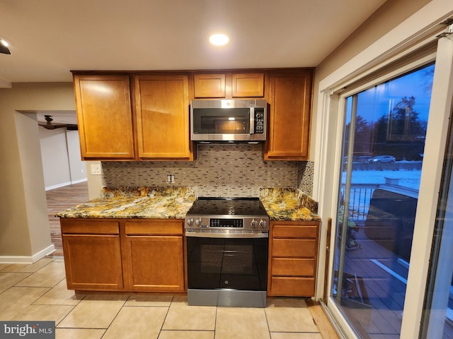 kitchen with decorative backsplash, light stone countertops, stainless steel appliances, and light tile patterned floors