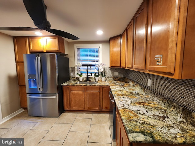 kitchen featuring stainless steel fridge, light stone counters, light tile patterned floors, and sink