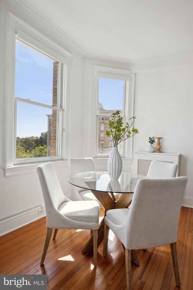 dining space with hardwood / wood-style floors and crown molding