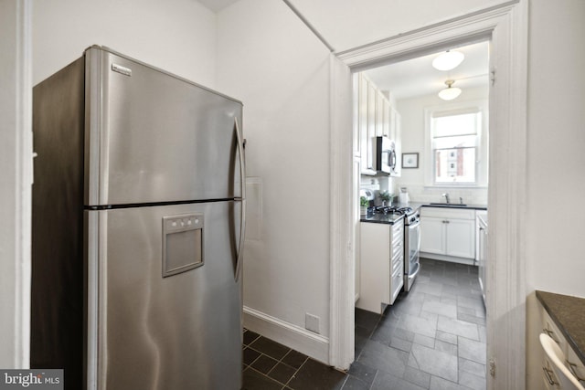 kitchen with decorative backsplash, white cabinetry, sink, and appliances with stainless steel finishes