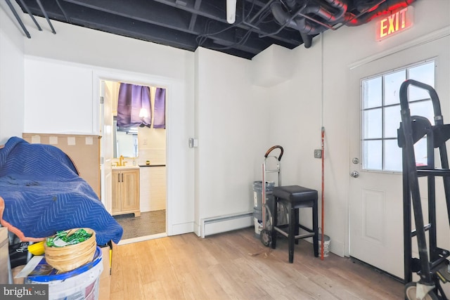 foyer entrance featuring light wood-type flooring, sink, and a baseboard radiator