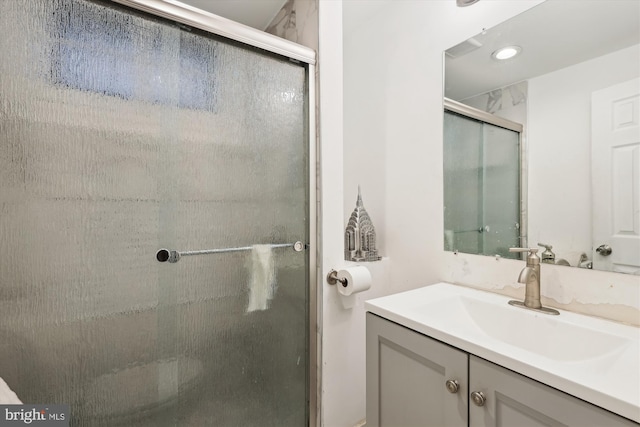 bathroom featuring a shower with shower door and vanity