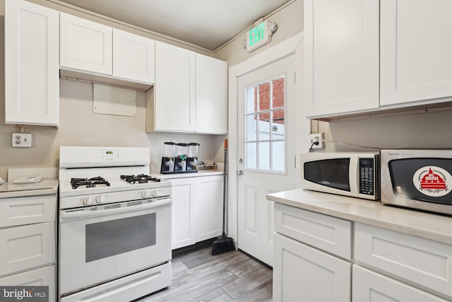 kitchen with light wood-type flooring, light stone countertops, white cabinetry, and white appliances