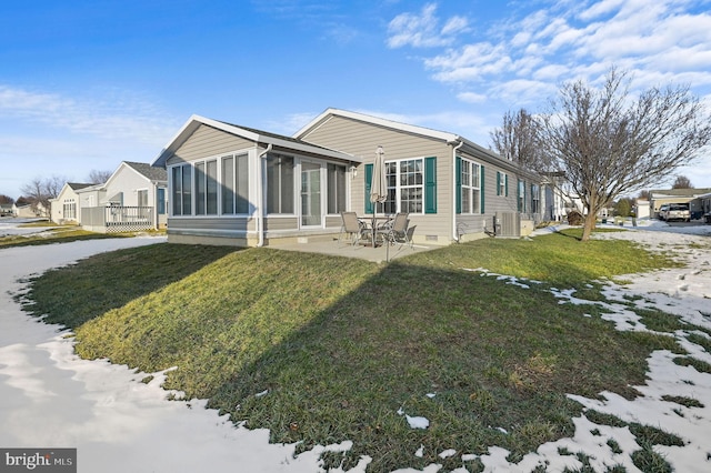 rear view of house with a sunroom, central AC unit, a patio area, and a lawn