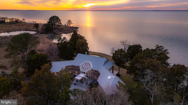 aerial view at dusk featuring a water view