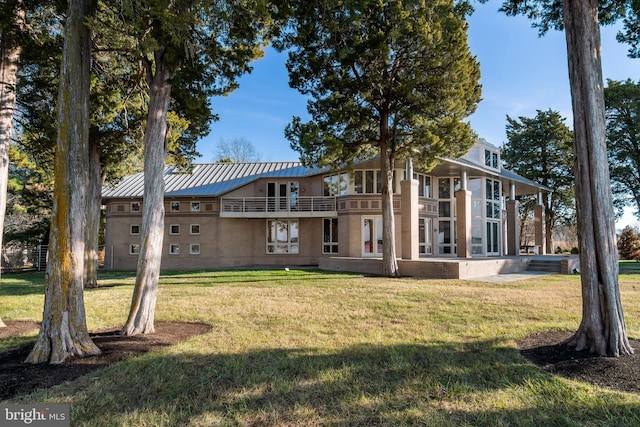 rear view of house featuring a yard and a balcony