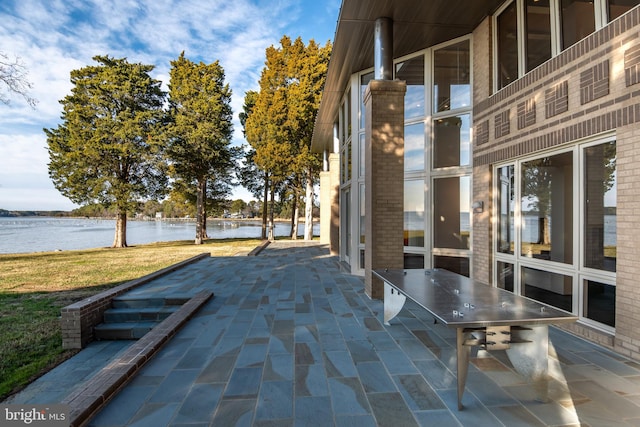 view of community featuring a yard, a water view, and a patio area