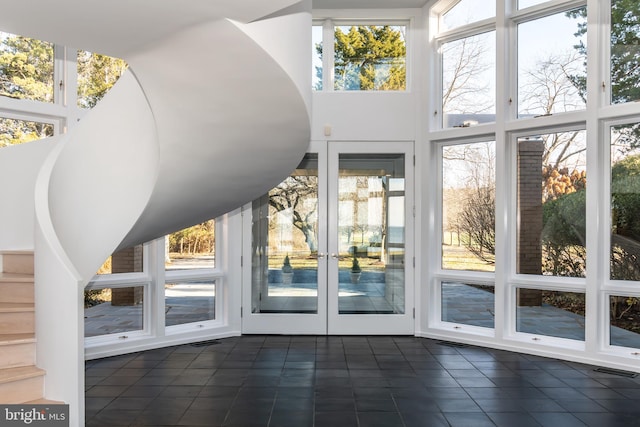 entryway featuring dark tile patterned flooring, a wall of windows, a towering ceiling, and french doors