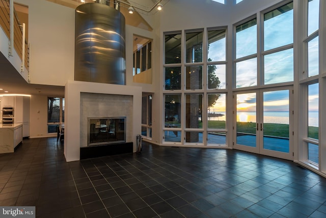 unfurnished living room featuring dark tile patterned floors, a towering ceiling, and a premium fireplace