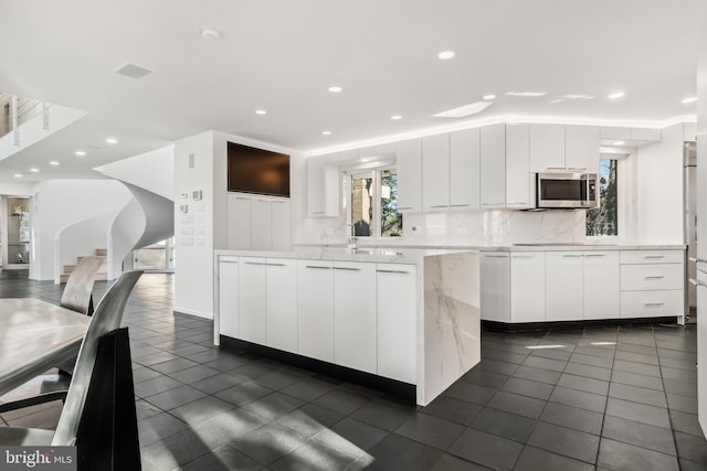 kitchen with dark tile patterned floors, white cabinetry, and backsplash