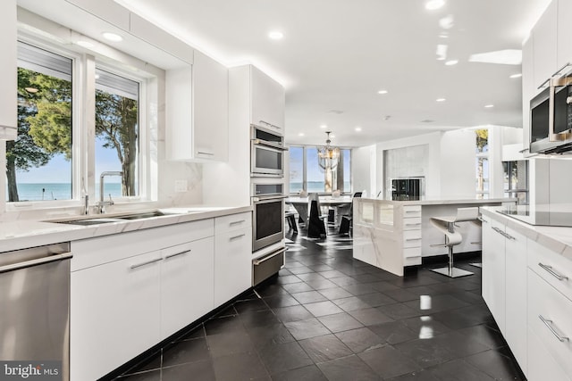 kitchen with white cabinets, sink, stainless steel appliances, and a water view