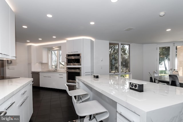 kitchen with white cabinets, light stone countertops, dark tile patterned floors, and stainless steel appliances