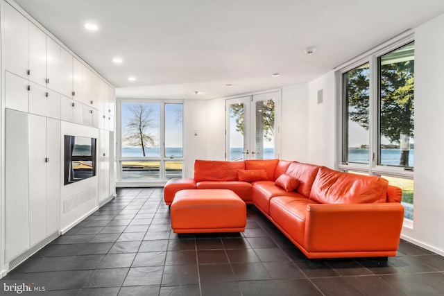 living room with expansive windows, french doors, and a water view