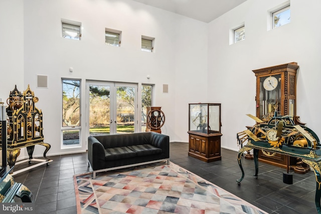 sitting room with dark tile patterned flooring, a towering ceiling, and french doors