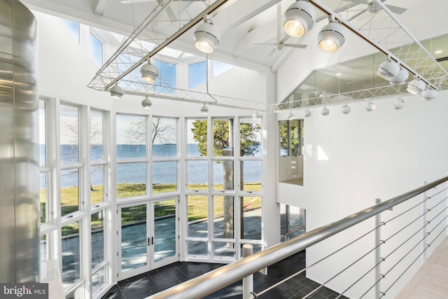 interior space with french doors, a water view, a wealth of natural light, and ceiling fan