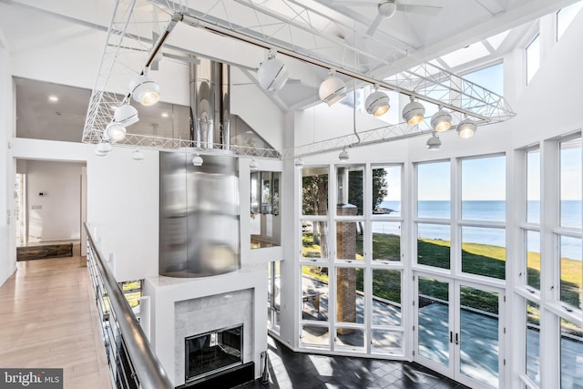 sunroom / solarium with a high end fireplace, french doors, a water view, and a healthy amount of sunlight