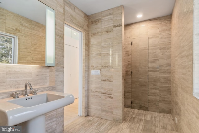 bathroom featuring tile patterned floors, a shower, sink, and tile walls