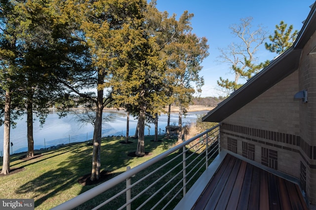 wooden terrace with a yard and a water view