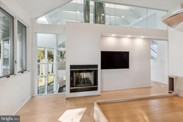 living room with a multi sided fireplace, high vaulted ceiling, and hardwood / wood-style flooring