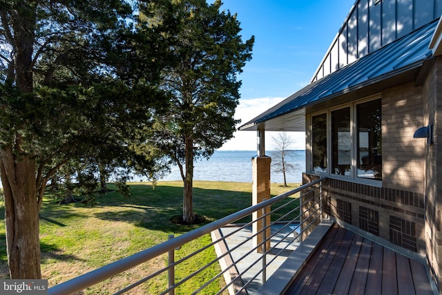 wooden terrace with a water view and a lawn