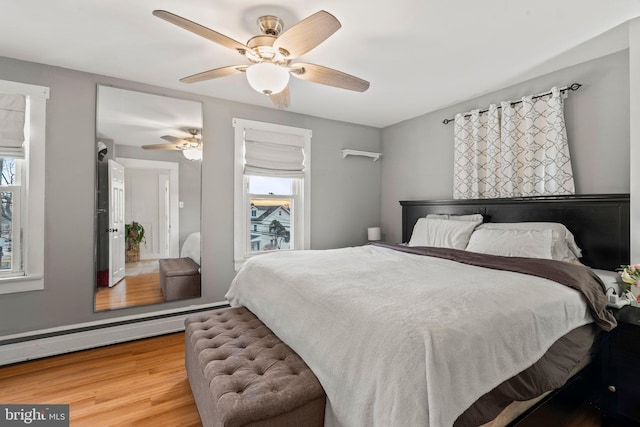 bedroom featuring baseboard heating, ceiling fan, and wood-type flooring