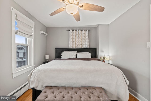 bedroom with hardwood / wood-style floors, ceiling fan, and a baseboard radiator