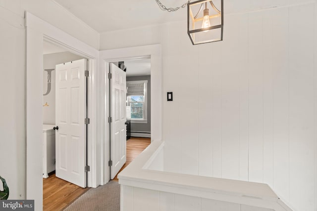 corridor with hardwood / wood-style floors and baseboard heating