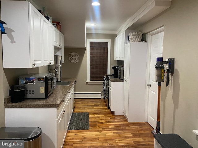 kitchen featuring light wood-type flooring, ornamental molding, a baseboard radiator, electric range oven, and white cabinetry