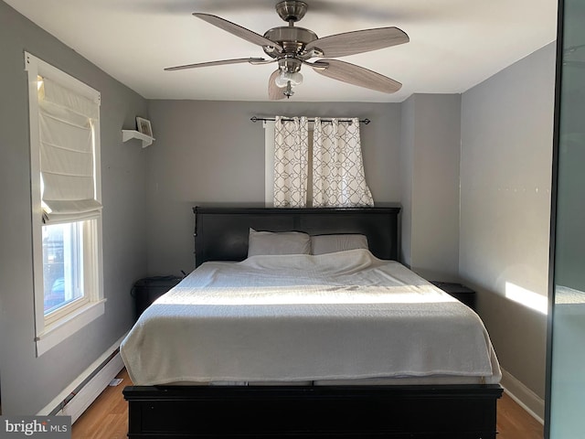 bedroom with ceiling fan, a baseboard radiator, and wood-type flooring