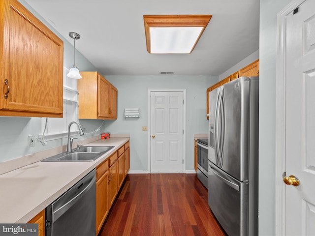 kitchen featuring sink, dark hardwood / wood-style floors, decorative light fixtures, and appliances with stainless steel finishes