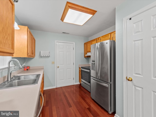 kitchen with appliances with stainless steel finishes, dark hardwood / wood-style floors, light brown cabinetry, and sink