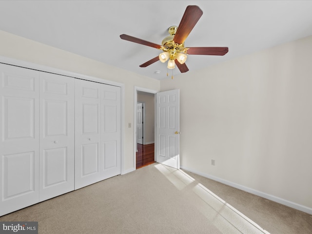 unfurnished bedroom featuring ceiling fan, a closet, and light carpet