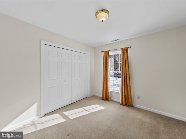 unfurnished bedroom with light carpet and a closet